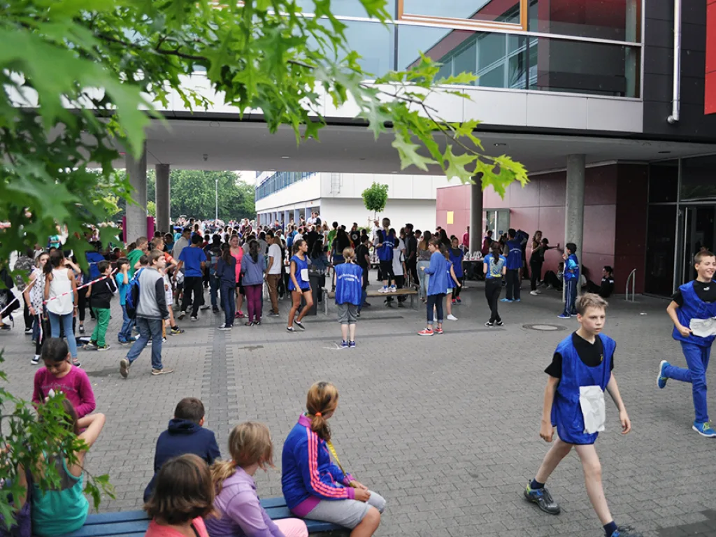 Blick auf den Schulhof mit Läufern und Publikum.